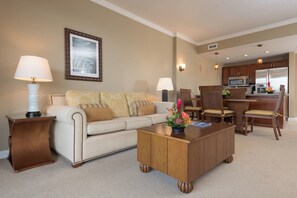 Een hotelkamer met een bank, salontafel, stoelen, een eettafel en een kitchenette.