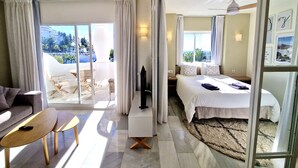 A hotel room with a bed, a TV, a desk, and a balcony with a view of the city. - SR Home La Cartuja 2 BDR wonderful sea view (Mijas)