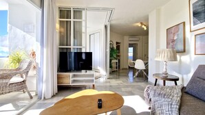 A modern living room with a flat-screen TV, a sofa, a dining area, and a balcony with plants. - SR Home La Cartuja 2 BDR wonderful sea view (Mijas)