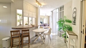 A modern kitchen with a dining area, large windows, and a view of the living room. - SR Home La Cartuja 2 BDR wonderful sea view (Mijas)