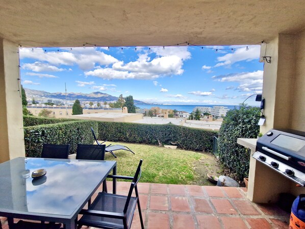 Une terrasse extérieure avec une table et des chaises, un barbecue et une vue sur le paysage urbain et les montagnes.