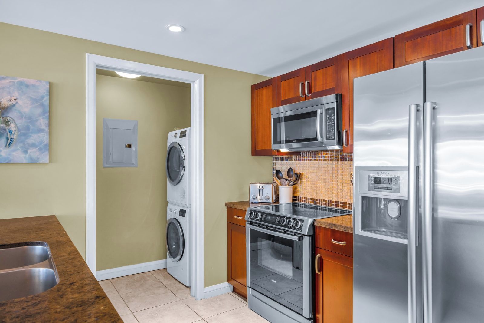A kitchen with a stainless steel refrigerator, a microwave, an oven, and a washing machine.