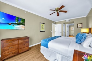 A hotel room with a bed, a wooden dresser, a ceiling fan, a framed picture, and a door leading to another room. - Honua Kai | Ocean View 5 BR, Sleeps 16 | Car Incl. w/ 6+ Nights | HKK ML-3565 by KBM (Lahaina)
