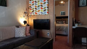 A modern living room with a sofa, a flat-screen TV, and a decorative wall piece.