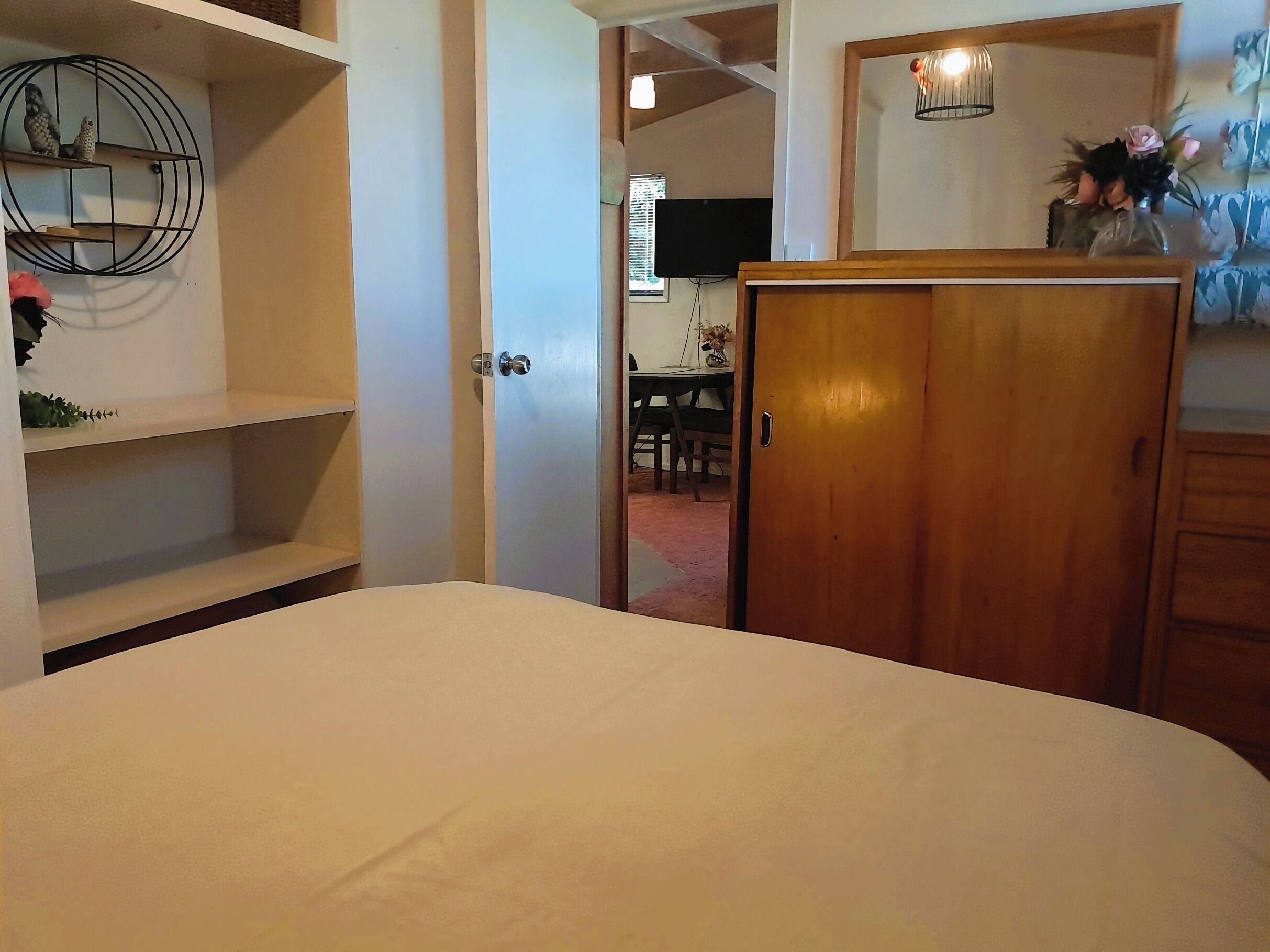 Une chambre à coucher comprenant un lit, une armoire et une étagère avec des objets décoratifs.