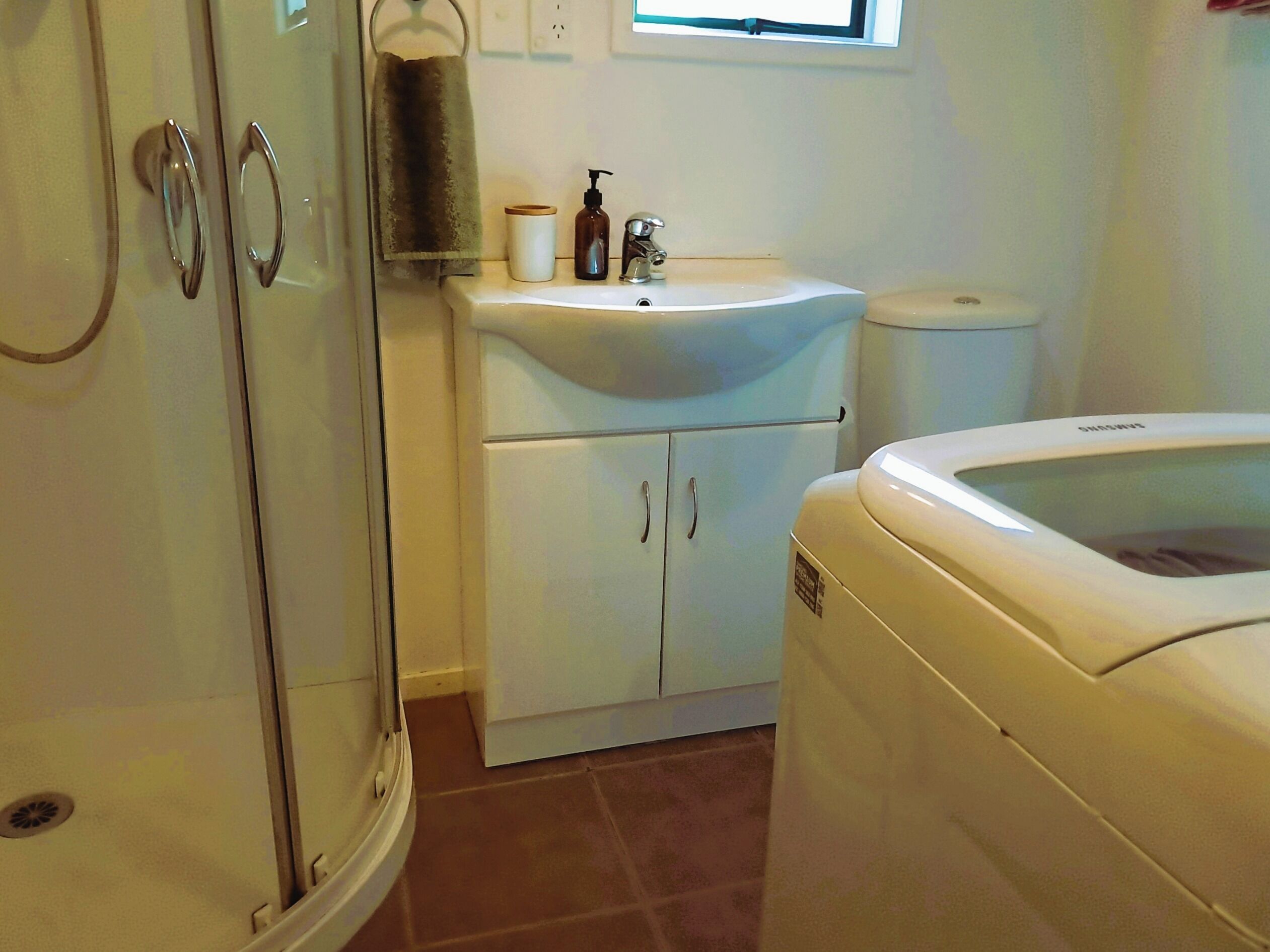 Une salle de bain équipée d’une douche, d’un lavabo, de toilettes et d’un lave-linge.
