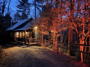 Une cabane avec une véranda, une allée en gravier et une clôture en bois.
