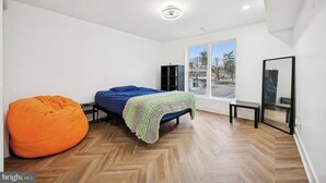 Ein Schlafzimmer mit Bett, Sitzsack, Fenster und Spiegel.