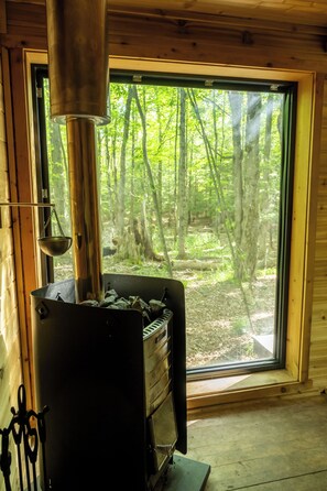 Ein Kaminofen mit Blick auf einen Wald durch ein Fenster.