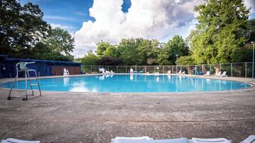 Une piscine équipée de chaises longues, d’une échelle et d’un espace abrité avec des sièges.