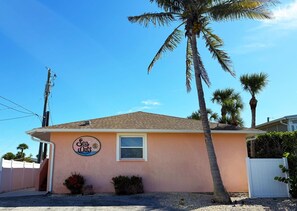 A single-story building with a 'Sea Oats' sign, palm trees, and a clear blue sky. - Sea Oats 1BR Condo – Pool, Beach, Boat Slip (Englewood)