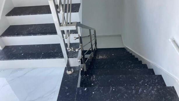 Un escalier avec des marches en marbre noir et une rampe en métal.