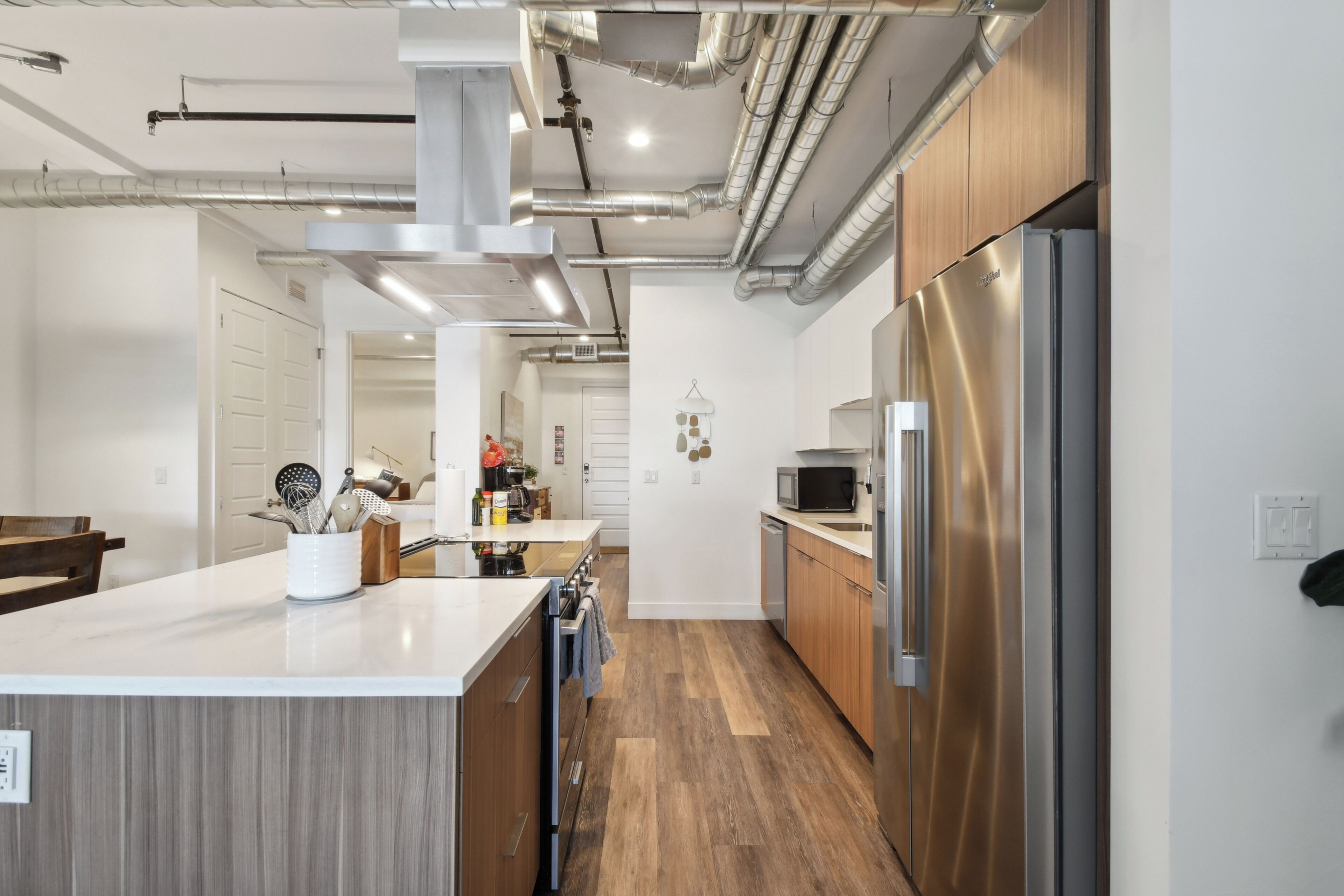 Una cocina moderna con electrodomésticos de acero inoxidable, armarios de madera y una isla central con utensilios de cocina.