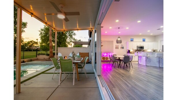 Eine moderne Küche mit weißen Schränken, ein Essbereich mit grünen Stühlen und ein Poolbereich mit Tisch und Stühlen.