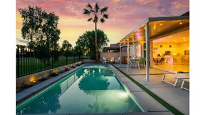Ein Schwimmbad mit Blick auf ein modernes Haus und einen Sonnenuntergang.