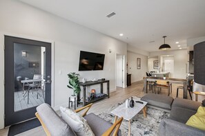 A modern living room with a sofa, a coffee table, and a TV mounted on the wall. - Golden Hour Designer Loft Espadin Lohi (Denver)
