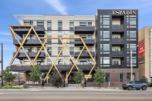 A modern building with a unique geometric facade, balconies, and a sign indicating it's for sale. - Golden Hour Designer Loft Espadin Lohi (Denver)
