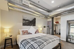 Une chambre à coucher moderne avec un lit, des tables de chevet, une commode et une grande fenêtre.