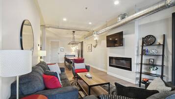 A modern living room with a sofa set, a coffee table, a fireplace, and a TV mounted on the wall.