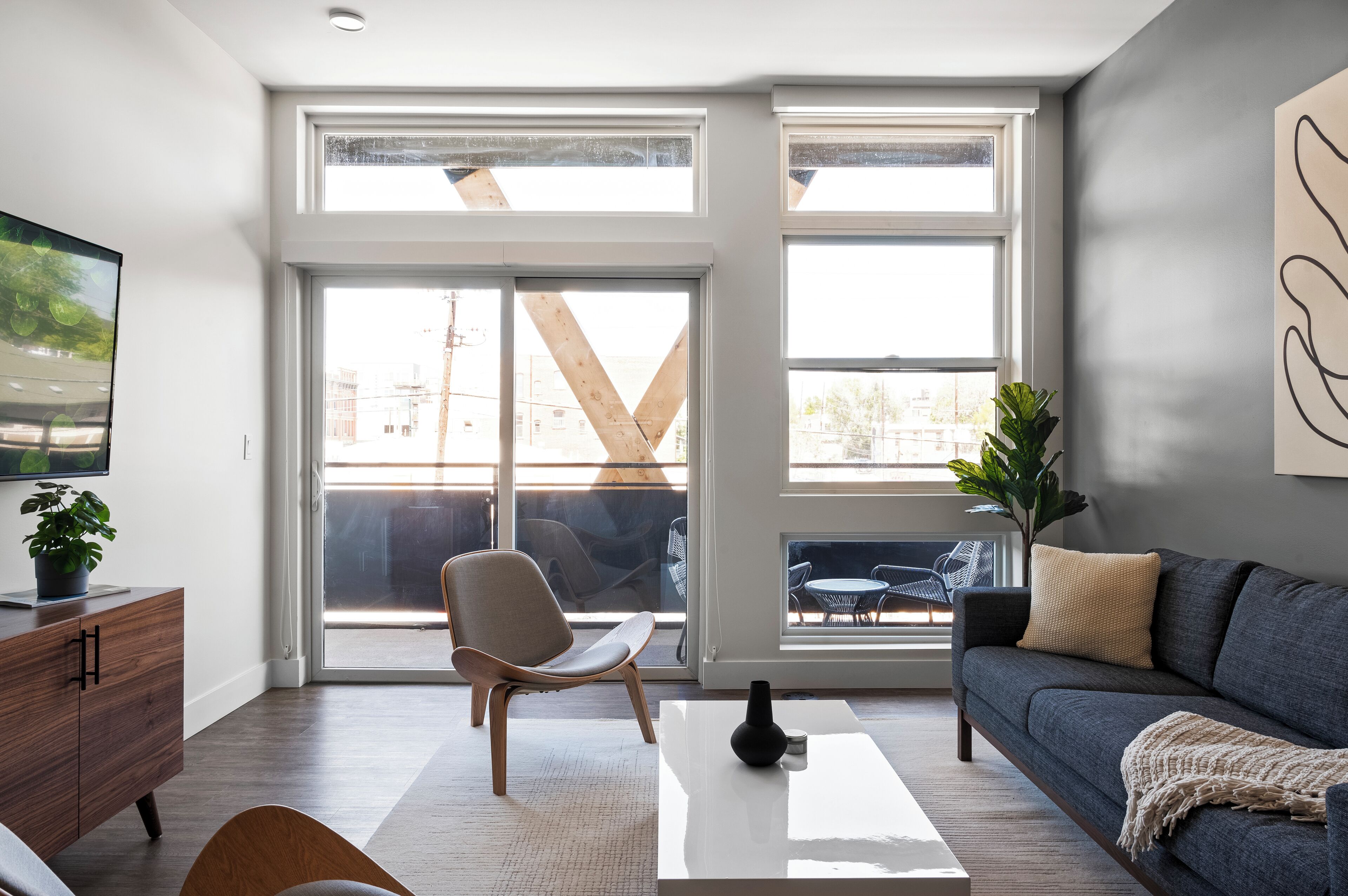 Een moderne woonkamer met een bank, een salontafel en een stoel. Er is een groot raam met uitzicht naar buiten.