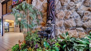 A stone wall with a wooden sculpture and a tiered water feature. - The Maui Wowi Oceanfront Condo (Daytona Beach Shores)