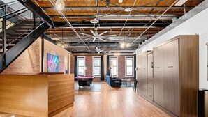 A spacious room with a wooden floor, a pool table, and a staircase with metal railings. - Suite [1] + [2] (Denver)