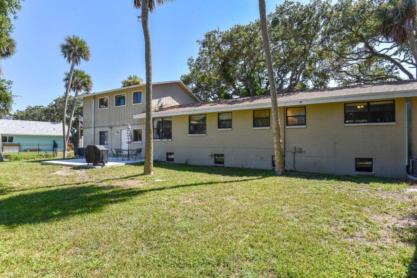 A two-story building with a flat roof, multiple windows, and a small patio area with outdoor furniture.