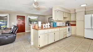 A modern kitchen with a central island, white cabinets, and a ceiling fan. - Sunset on the Peninsula (Daytona Beach)