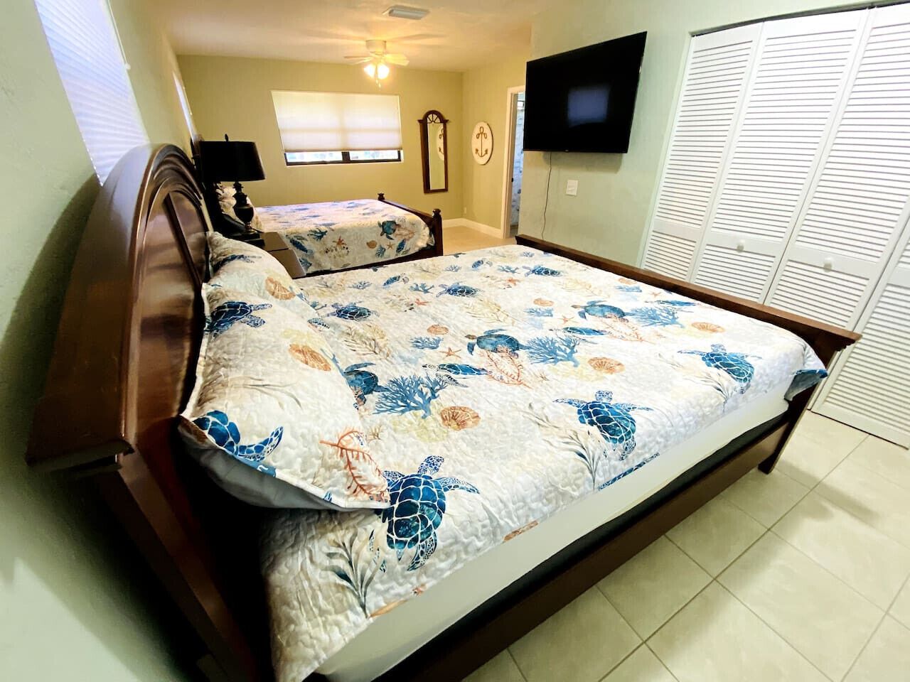 A bedroom with a large bed, a TV mounted on the wall, and a closet with sliding doors.