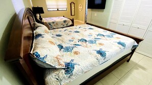 A bedroom with a large bed, a TV mounted on the wall, and a closet with sliding doors. - Sunset on the Peninsula (Daytona Beach)