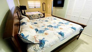 A bedroom with a large bed, a TV mounted on the wall, and a closet with sliding doors.