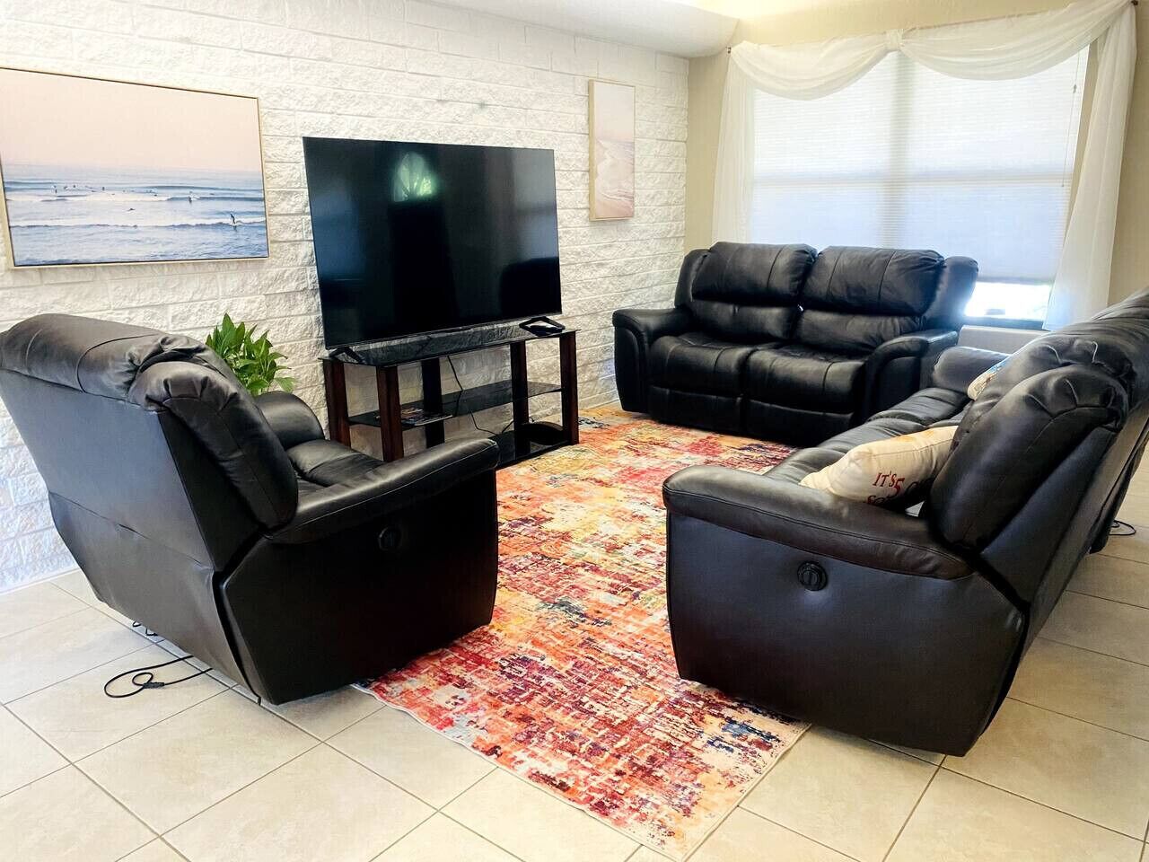 Uma sala de estar com dois poltronas de couro preto, uma televisão de tela plana e um tapete estampado.