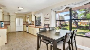A spacious kitchen with a dining area, large windows, and a view of the outdoors. - Sunset on the Peninsula (Daytona Beach)