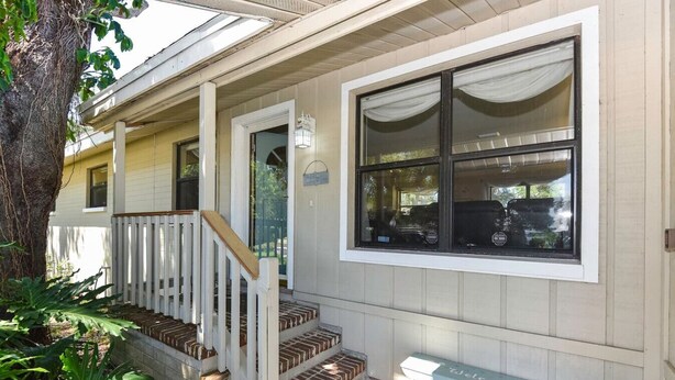 A two-story building with a porch, a bench, and a large window. - Sunset on the Peninsula (Daytona Beach)