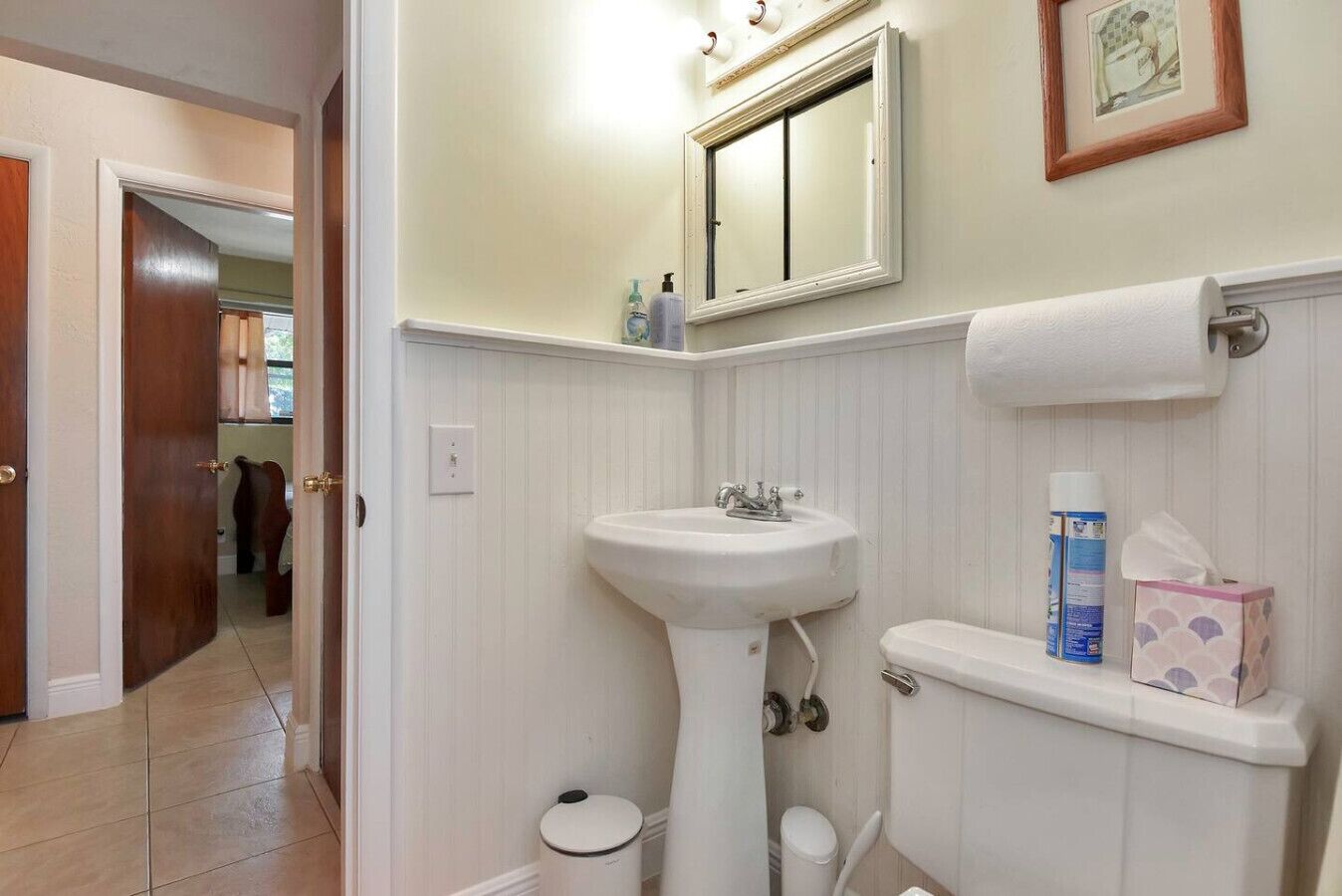 Un bagno con un lavandino su piedistallo, il water e un piccolo ripiano con articoli da toilette.