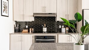 Eine moderne Küche mit hellen Holzschränken, einer schwarzen Küchenrückwand und einem eingebauten Geschirrspüler.