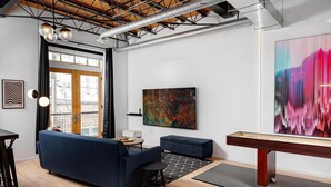 Een moderne woonkamer met een blauwe bank, een bijzettafeltje en een groot abstract schilderij.