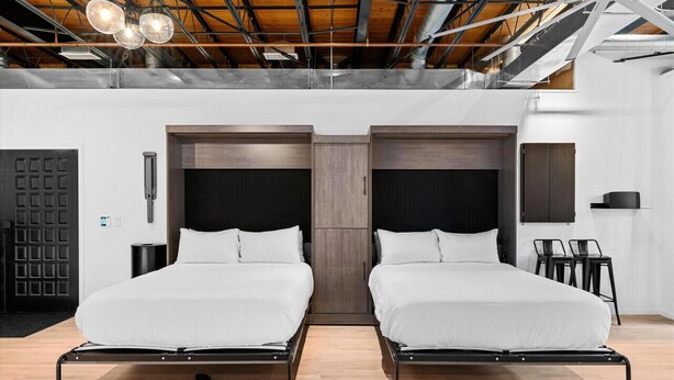 Een moderne slaapkamer met twee bedden, een houten plafond en een zwarte deur.