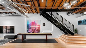 Een moderne kunstgalerie met een houten vloer, een pooltafel en een trap.