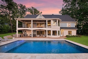 Ein zweistöckiges Haus mit Swimmingpool, großen Fenstern und einer überdachten Terrasse.