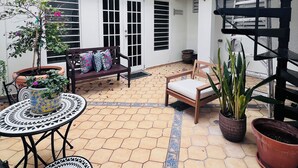 A courtyard with a patio area, a wooden bench, a round table, and potted plants. - Elegant Colonial Retreat in Mayagüez - 2BR/2BA (Mayagüez)
