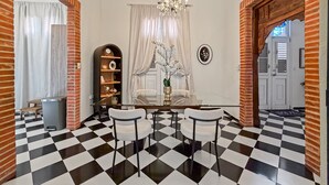 A dining area with a checkered floor, a chandelier, and a white table with chairs. - Elegant Colonial Retreat in Mayagüez - 2BR/2BA (Mayagüez)