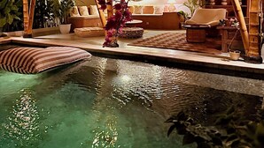 A pool area with a lounge chair, a small table, and a decorative plant. - Casa Alonia (Uluwatu)