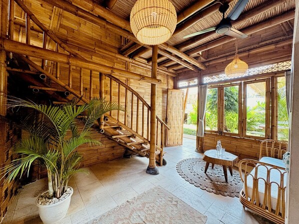 Un intérieur en bois avec un escalier, de grandes fenêtres et un luminaire suspendu.