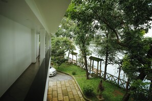 A balcony with a view of a water body, surrounded by greenery and a wooden fence. - DREAM LAND VIEW RESORT (Kanayannur)
