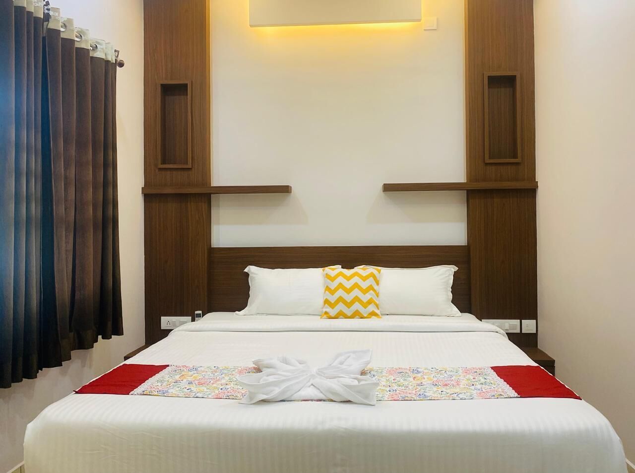 A neatly made bed with white linens, a decorative pillow, and a folded towel on the bed.