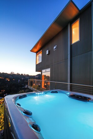 Een modern huis met twee verdiepingen en een jacuzzi op het balkon.