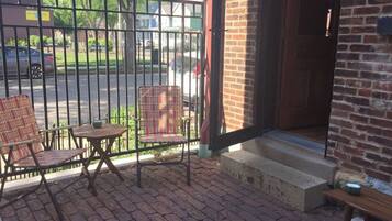 A patio with two chairs and a small table, a brick wall, and a metal gate.