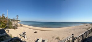 A beach with a wooden boardwalk, a sandy shore, and a clear blue sky. - Sandy Bottom: Cozy Up by the Lake | Hot Tub + Fall Views (Ocqueoc)