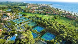 Luchtbeeld van een resort met meerdere tennisbanen, een golfbaan en een strand.